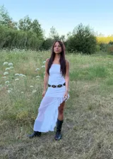 Vestido largo blanco de corte recto con escote strapless y falda con volados en el ruedo que aportan transparencia y movimiento.