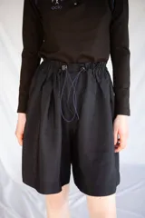 Bermuda holgada negra con cintura elastizada y hebillas de ajuste.