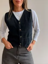 Chaleco de pana fina con escote en V y cierre frontal de botones. Presenta un diseño entallado con costuras verticales que definen la silueta.