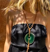 Collar con dije de piedra ágata en tonos morados suspendido de un tiento de cuero.