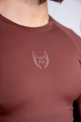 Remera de lycra de manga larga, corte ajustado, color marrón, con cuello redondo y logo bordado en el centro del pecho.