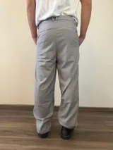 Pantalón sastrero de corte recto y holgado, color gris claro, con pinzas frontales y cintura con elástico posterior.