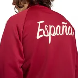 Campera deportiva Adidas de la selección de España, color rojo bordó con las clásicas tres tiras blancas en las mangas, cuello alto y cierre frontal completo. Presenta el logo de Adidas Originals y el escudo de la selección bordados en el pecho.