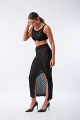 Conjunto de top y pollera negra de tejido de punto calado con rayas diagonales. El top es corto y sin mangas, la pollera es larga con tajo lateral.