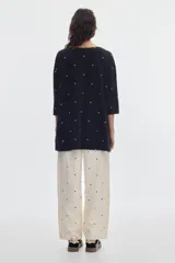 Vestido corto negro con estampado de lunares blancos, escote redondo y mangas 3/4.