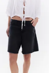 Bermuda de denim negro tipo jeans, con tiro medio, bolsillos traseros con bordado en contraste y ruedo desflecado.