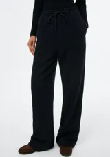 Pantalón de corte recto y holgado, color negro, con cintura elástica y cordón ajustable. Presenta costuras verticales frontales y bolsillos laterales.