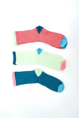 Pack de tres pares de medias crew de diseño colorido y estampado variado. Incluye un par a rayas rojas con talón azul y puntera celeste, un par verde claro con lunares blancos, talón azul y puntera rosada, y un par azul con rayas, talón verde claro y puntera celeste.