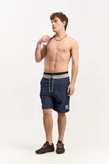 Short de baño azul marino con cintura gris y cordón ajustable blanco y gris, con un pequeño parche estampado en la pierna izquierda.