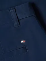 Pantalón chino de corte slim fit, color azul marino, confeccionado en mezcla de algodón y elastano. Presenta cierre de botón y cremallera, cuatro bolsillos y viene con un cinturón a rayas blancas, rojas y azules.