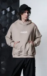 Hoodie oversize color gris topo, confeccionado en rústico de algodón, con capucha forrada, bolsillo canguro y costuras expuestas en mangas y ruedo. Presenta estampa gráfica en la espalda con la palabra AMOR y diversos motivos románticos.