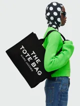 Bolso tote de gran tamaño en color negro, confeccionado en lona resistente. Presenta el logo distintivo de la marca estampado en blanco en el frente y doble asa superior para llevar al hombro.