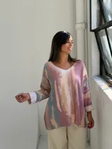 Sweater de punto con diseño abstracto en tonos rosados, beige y azul, de corte holgado, cuello en V y mangas largas con puños vueltos.
