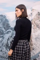 Polera de tejido de punto fino color blanco, con cuello alto, mangas largas y terminaciones con detalle de ondas en puños, cuello y ruedo.