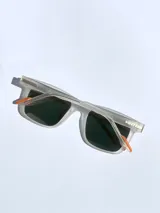 Lentes de sol con armazón de acetato traslúcido en acabado mate y cristales polarizados con efecto espejado en tono naranja. Presentan detalles en color naranja en las patillas y el frente.