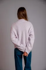 Buzo negro de tejido texturizado con apliques de flores de crochet en colores rosa pálido, amarillo y azul. Tiene cuello redondo y mangas largas.