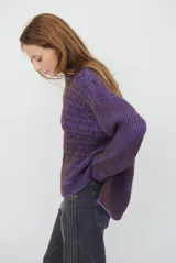 Buzo reversible de tejido de punto con diseño de trenzas, cuello redondo y mangas largas. Presenta una combinación de colores en contraste, con un lado en violeta y el otro en marrón oscuro.