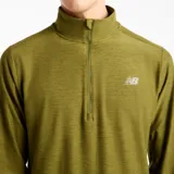 Buzo deportivo New Balance de hombre, de manga larga, con cuello alto y medio cierre frontal. Presenta diseño space dye en tono verde militar y logo reflectante en el pecho.