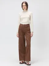 Pantalón de tiro medio y pierna ancha confeccionado en denim de algodón grueso. Presenta un diseño a rayas verticales en tonos azul y celeste, con costuras en contraste color rojo, bolsillos laterales tipo cargo y remaches metálicos.