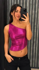 Top fucsia metalizado de un solo hombro, con diseño ajustado y dobladillo asimétrico.