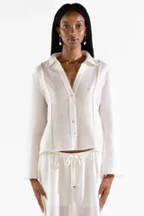 Camisa de manga larga de crepé color crema, con escote en V, cuello camisero, botones frontales y mangas amplias de caída fluida.