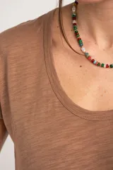 Remera de algodón flame color blanco marfil, con cuello redondo amplio y mangas cortas holgadas.