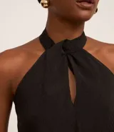 Blusa negra sin mangas confeccionada en chiffon, con cuello halter y abertura en forma de gota en el escote.