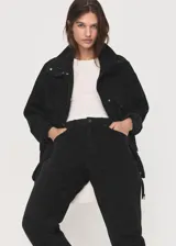 Anorak de estilo utilitario confeccionado en tejido de algodón tipo denim, con diseño oversize, cuello embudo, cierre frontal de cremallera y botones a presión, y cuatro bolsillos de parche con solapa en la parte delantera.
