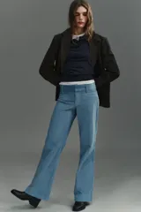 Pantalón de tiro alto con corte flare, confeccionado en pana. Presenta cintura ancha con trabillas, falsos bolsillos delanteros y cierre frontal con cremallera, botón oculto y ganchos metálicos.