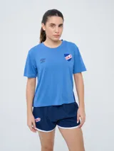 Remera deportiva de manga corta Umbro para mujer, de color azul con cuello redondo, diseño de tejido microperforado, logo de la marca en el pecho y escudo del Club Nacional de Football.