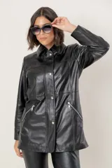 Campera de cuero en tono azul con efecto gastado, de corte recto y largo medio. Presenta cuello camisero, cierre frontal con botones a presión ocultos bajo una solapa y bolsillos laterales con cierre metálico.