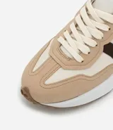 Championes estilo jogging con diseño de paneles en tonos gris, blanco y negro. Presentan cierre por cordones, suela de goma con relieve que se extiende hacia el talón y acabado en poliuretano.