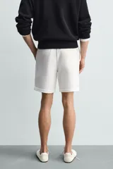 Bermuda regular fit de tejido elástico color blanco, con cintura elástica ajustable mediante cordón, bolsillos delanteros y bolsillos traseros de vivo.