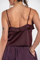 Musculosa negra de satén con escote en V, tirantes finos y detalle de volados en el pecho.