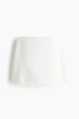Short pollera en tejido liviano de mezcla de lino y viscosa, de corte ajustado y color blanco.
