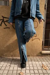 Pantalón de jean azul con cierre metálico en la parte inferior de la pierna.