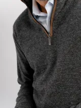Buzo de tejido de punto color beige con cuello alto y cierre frontal parcial. Presenta puños y ruedo acanalados.