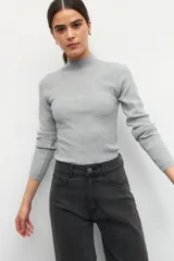Polera de tejido de punto acanalado en color crema, con cuello alto y manga larga, de ajuste ceñido al cuerpo.