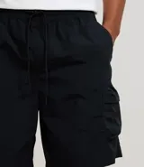 Bermuda cargo negra de tejido tecnológico (poliamida), con corte holgado, bolsillos laterales funcionales y cintura elástica con cordón ajustable.