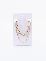 Collar dorado de doble cadena, una gruesa con eslabones grandes con detalles de color y otra fina con eslabones pequeños.