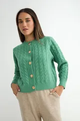 Cardigan de punto con diseño de trenzas, color verde, de corte recto y manga larga. Presenta cuello redondo y cierre frontal con botones dorados.
