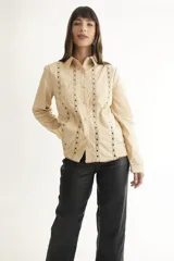 Camisa color beige claro con bordados florales y geométricos en el frente y cuello.
