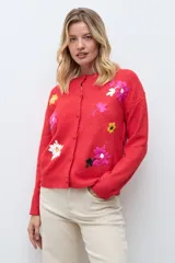 Cardigan de punto color rojo con cierre frontal de botones y bordados de flores en diversos colores. Presenta cuello redondo y mangas largas con puños acanalados.
