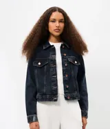Campera de jean con corte boxy, cuello clásico, cierre frontal con botones metálicos, bolsillos con solapa en el pecho y costuras reforzadas.