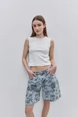 Bermuda de jean de calce amplio y largo a la rodilla, con estampado floral oscuro sobre fondo de mezclilla celeste. Cuenta con cinco bolsillos, trabillas para cinto y cierre frontal con botón y cremallera.
