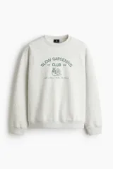 Buzo de cuello redondo en mezcla de algodón color gris melange, con diseño bordado frontal que incluye texto y el dibujo de un caracol.