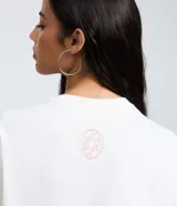 Remera blanca de algodón con cuello redondo y mangas cortas. Presenta un estampado fotográfico frontal de la banda Katseye con el nombre del grupo impreso en letras rojas en la parte inferior.