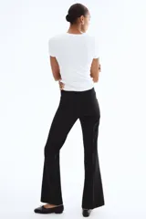 Pantalón negro de tiro alto con cierre y botón. Modelo de corte ajustado con bolsillos parche adelante con solapa y botón a presión, y piernas acampanadas con pliegues.