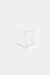 Top tipo corset de escote corazón y hombros descubiertos, con varillas interiores para estructura. Presenta cierre frontal con ganchos metálicos y ajuste en la espalda mediante cordones cruzados.