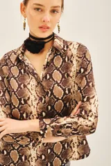 Camisa de manga larga con cuello camisero y corte masculino, confeccionada en poliéster con estampado de piel de serpiente en tonos marrones y beige.